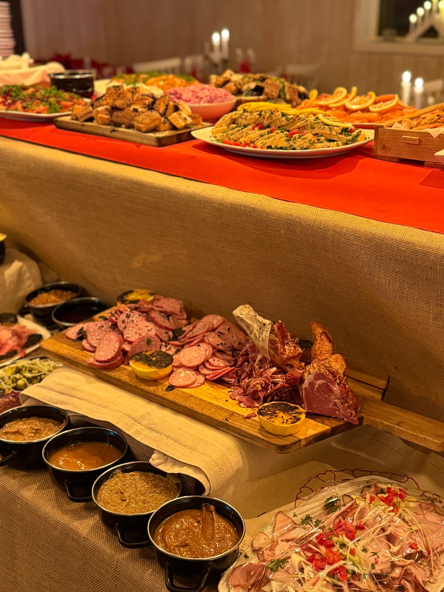 Julbord med kött, korv, såser och sallader uppdukat i flera nivåer